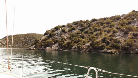 Segeln-Auf-Einer-Yacht-Ruhig-Durch-Eine-Hügelige,-Leicht-Bewaldete-Küste-In-Einem-Südeuropäischen-Land-An-Einem-Sonnigen-Sommertag