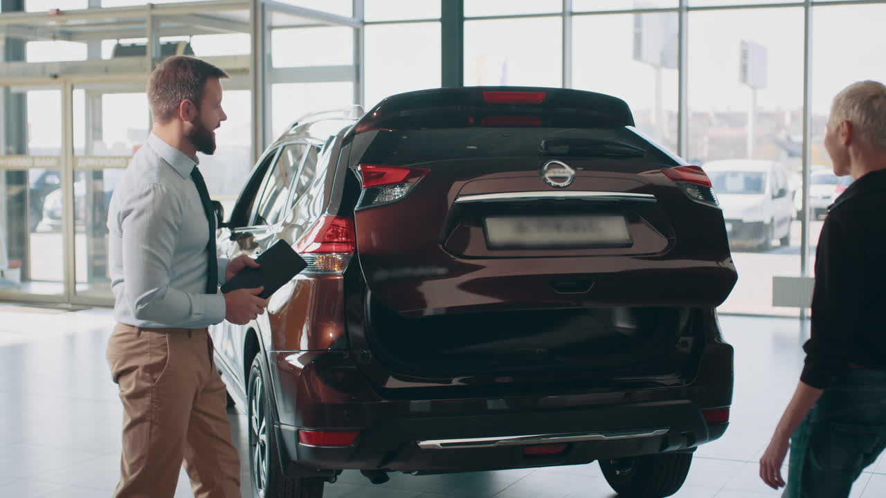 vendedor de automóviles mostrando el maletero de un suv al cliente en el concesionario