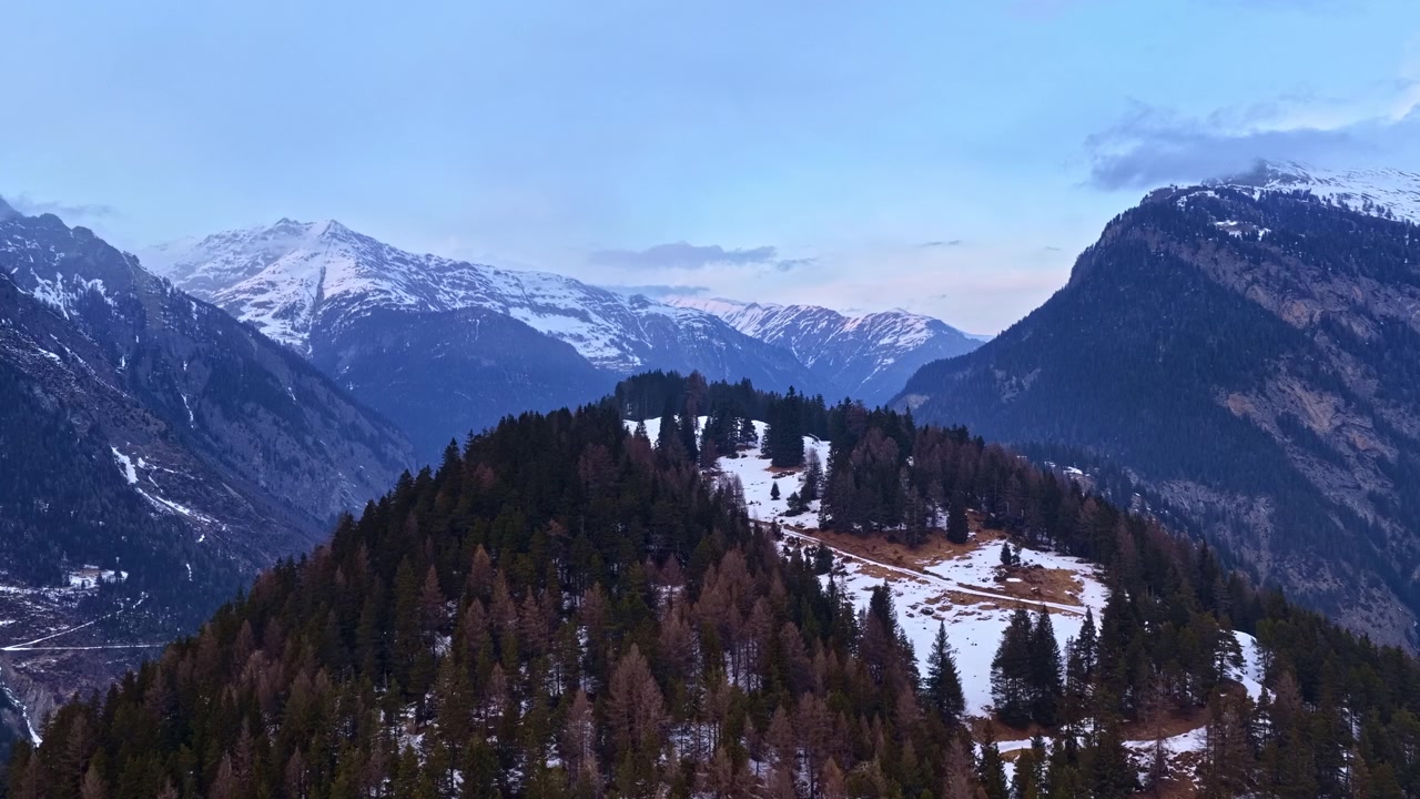 Cresta montuosa innevata circondata da cime spettacolari e una valle panoramica sotto un cielo azzurro.