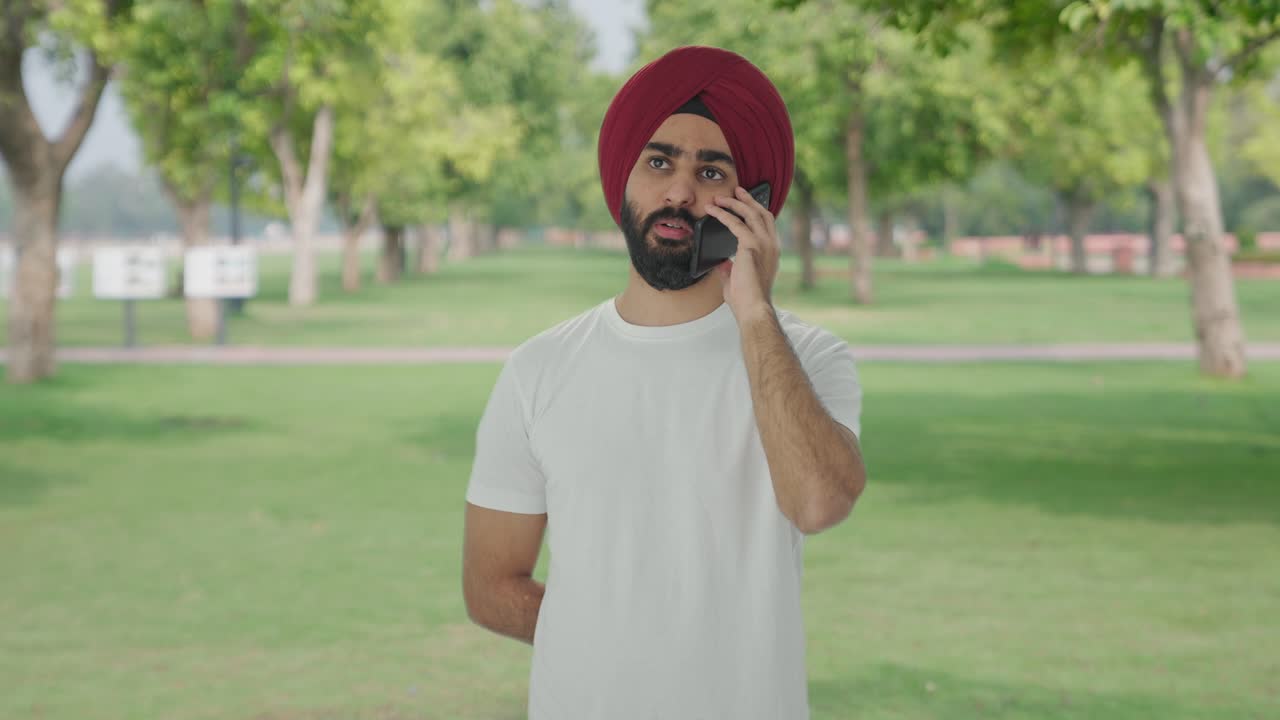 Uomo indiano Sikh che parla al telefono in un parco