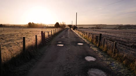 Golden-sunrise-along-a-dirt-road-in-a-rural-area-of-Scotland-in-winter-in-Perth-Shire,-United-Kingdom