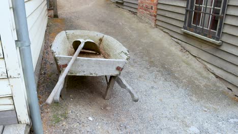 a wheelbarrow rests in a narrow alley between wooden buildings in sovereign hill, melbourne. overcast lighting creates a calm atmosphere