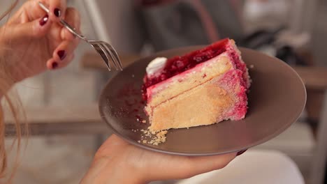 una mujer joven está sentada y comiendo un trozo de pastel de bodas