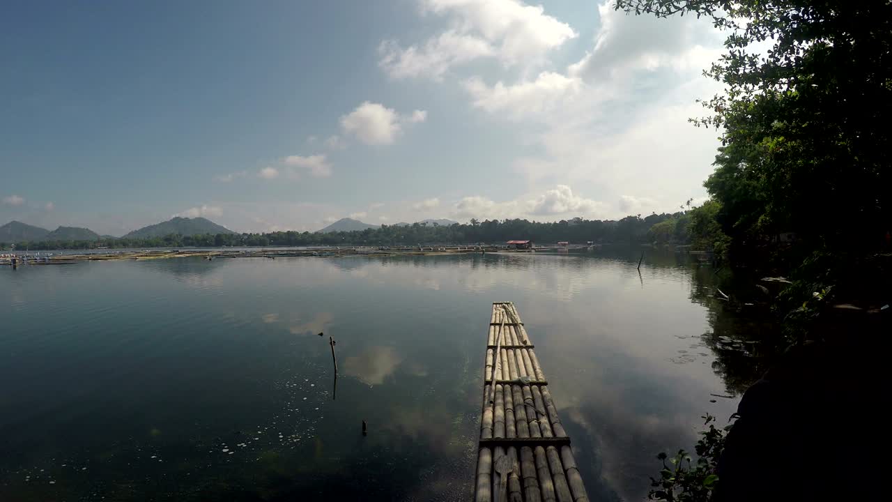 una balsa de bambú flotando en un lago contaminado en un día nublado