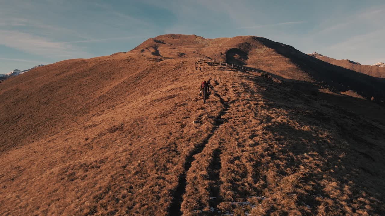 Ripresa che segue un escursionista su un prato in autunno al tramonto