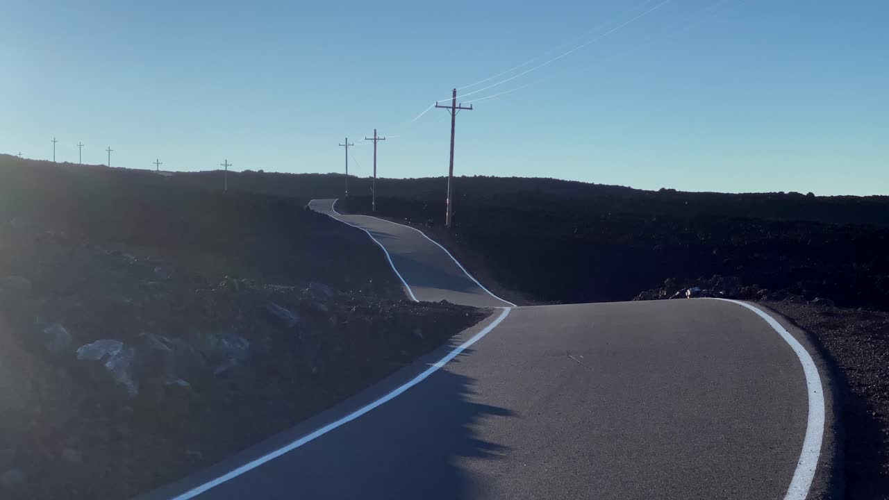 Sunset on winding Mauna Loa access road with telegraph poles