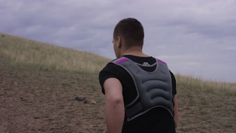 man running with weighted vest on a hill