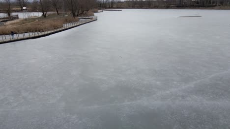 flight over frozen lake breaking ice in rural village, poland