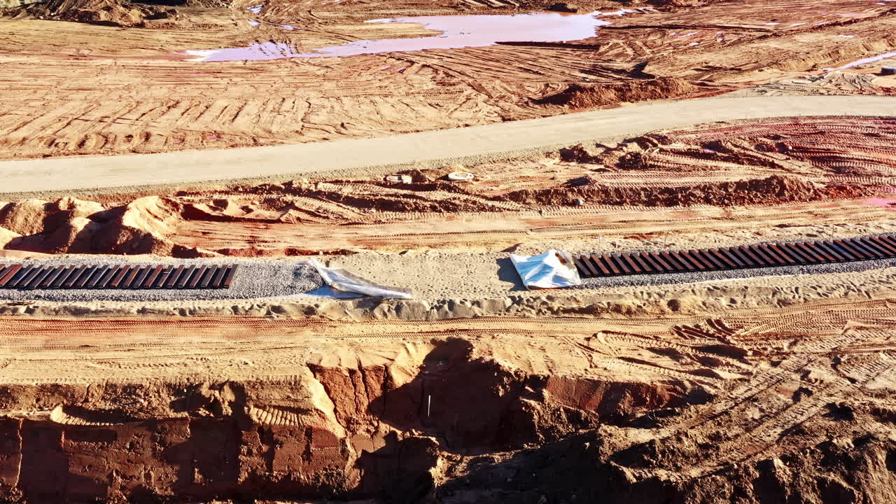 Dirt construction site with metal pipes and railway tracks under progress in dry terrain