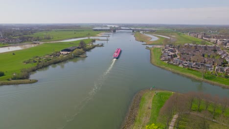 Reversing-rising-aerial-view-of-red-boat-on-ricer-in-Dutch-countryside