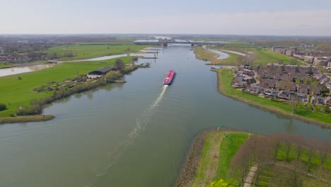 reversing rising aerial view of red boat on ricer in dutch countryside