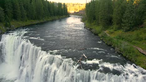 Drone-Aerial-pulling-back-of-the-Upper-Mesa-Falls,-a-thunderous-curtain-of-water-–-as-tall-as-a-10-story-building-Near-Island-Park,-and-Ashton,-Idaho