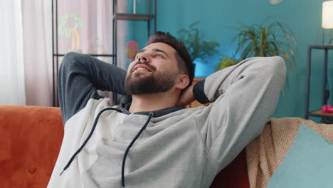 tired young man lying down on comfortable couch, taking a rest, daytime nap relaxing falling asleep