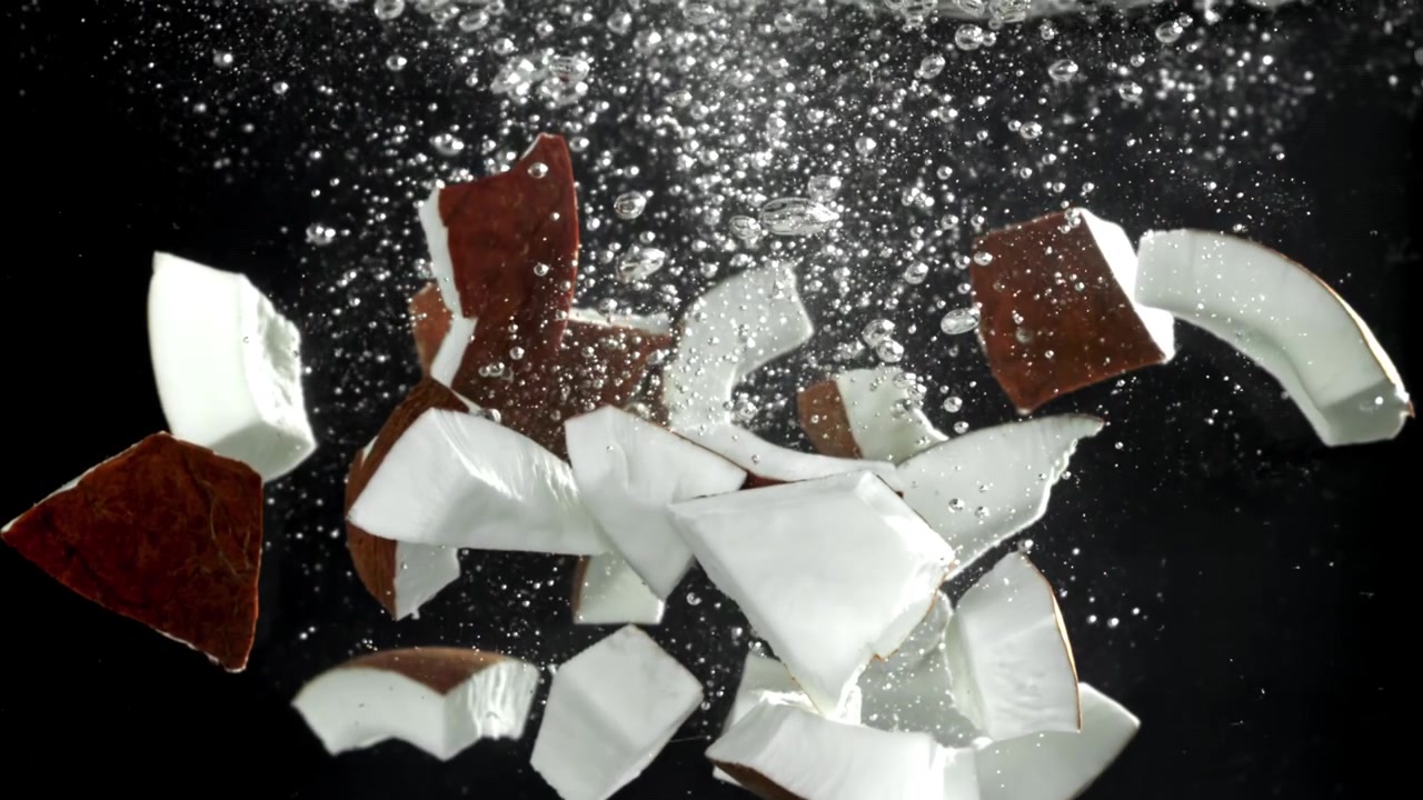 Pezzi di cocco fresco sommersi nell'acqua con bolle in risalita