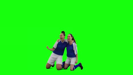 Video-of-two-caucasian-female-football-players-cheering-and-copy-space-on-green-screen