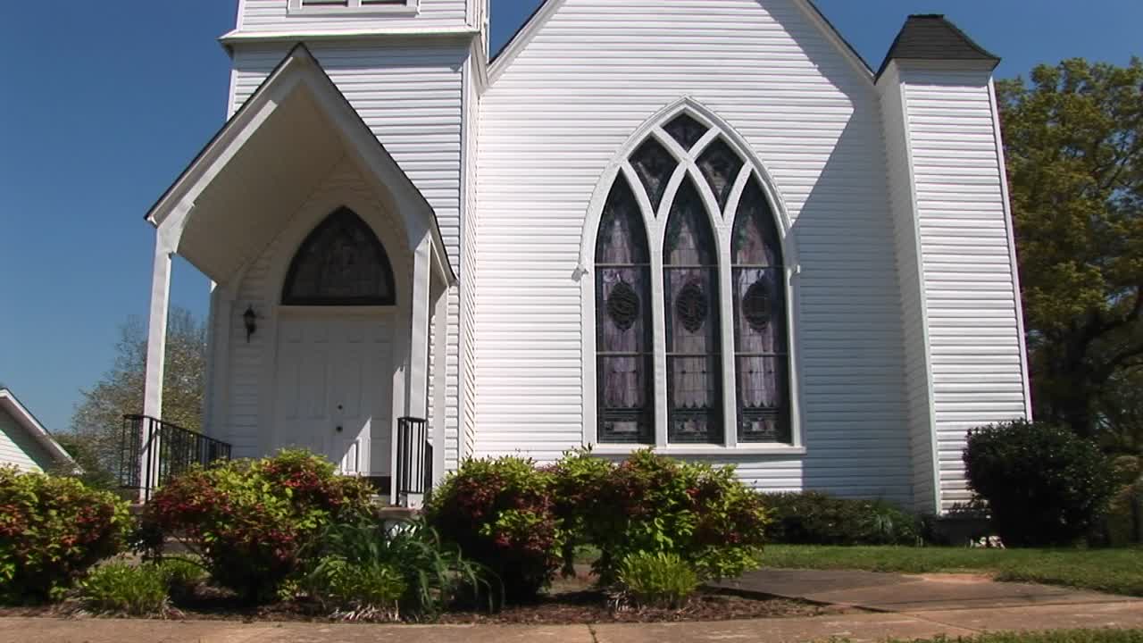 이 패닝 샷에서 오래된 시골 교회의 흰색 물막이 판자 외관이 푸른 하늘을 배경으로 설정되어 있습니다.
