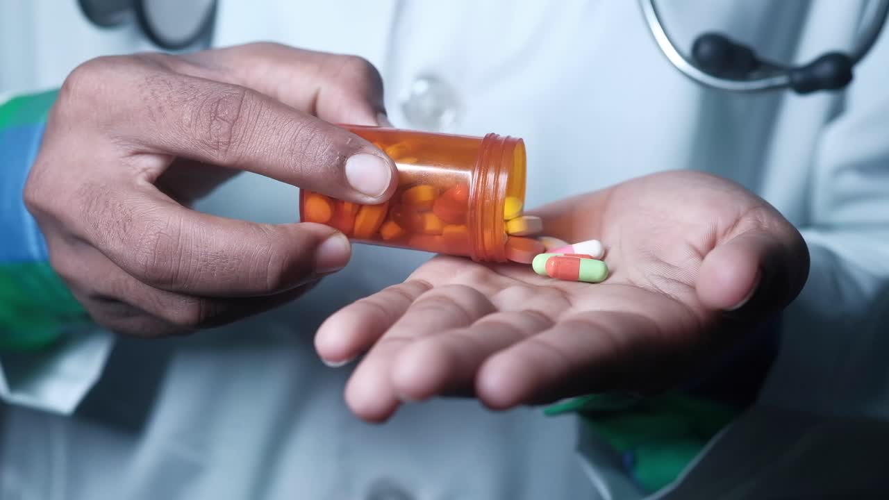 Mani del medico che dispensano pillole