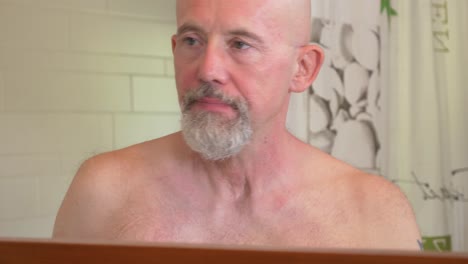 caucasian man brushes his teeth in a bathroom, view in a mirror