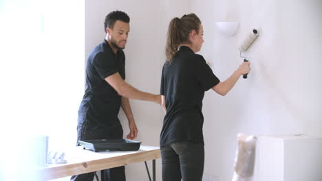 two people from a decorating team painting wall with rollers