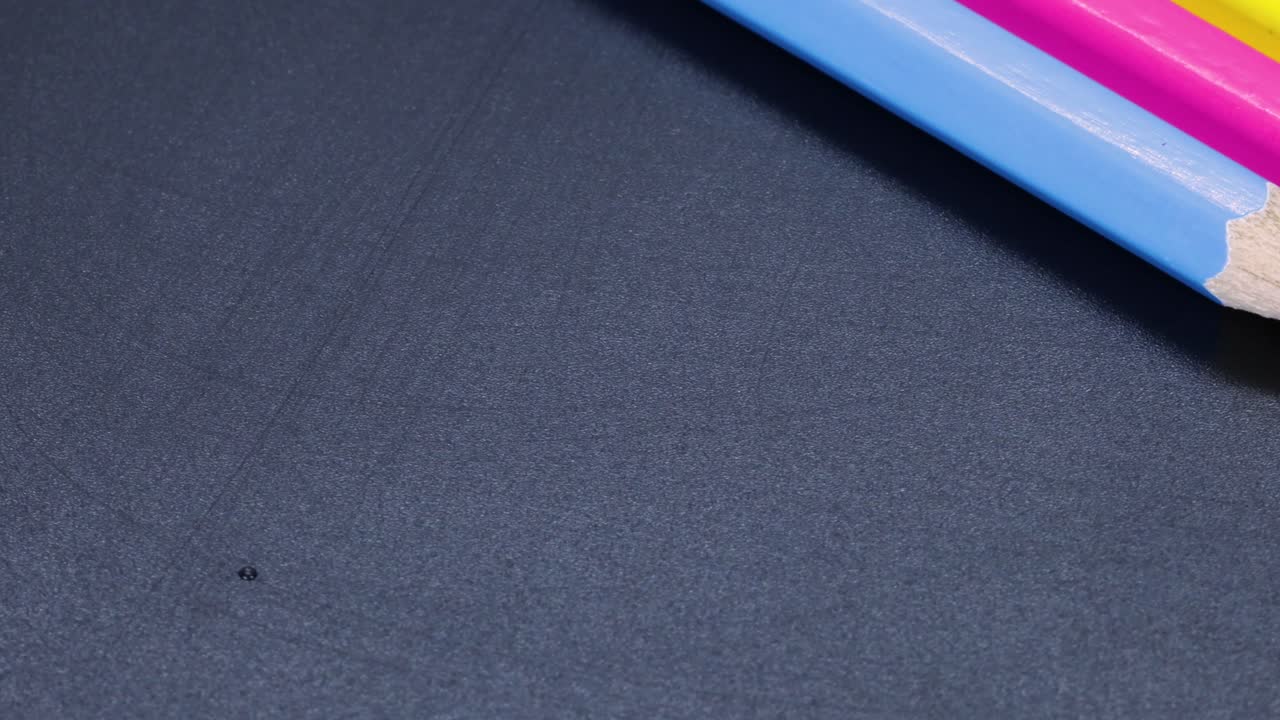 Cyan, magenta og gule farveblyanter roterer langsomt i 4k, makrooptagelse.