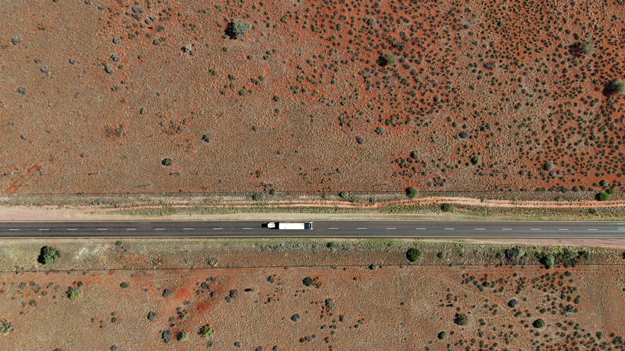 Coach with trailer drive on road through barren Karoo landscape, overhead aerial