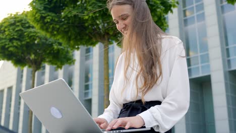 Happy-attractive-woman-working-with-laptop-near-office-building,-static-view