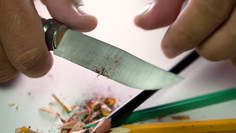 Footage-of-hands-slowly-sharpening-a-pencil-and-some-coloured-pencils-with-a-sharp-knife