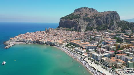 Cefalu-City,-Beach,-Rock-and-Boulevard-during-Summer-in-Sicily,-Italy---Aerial-4k