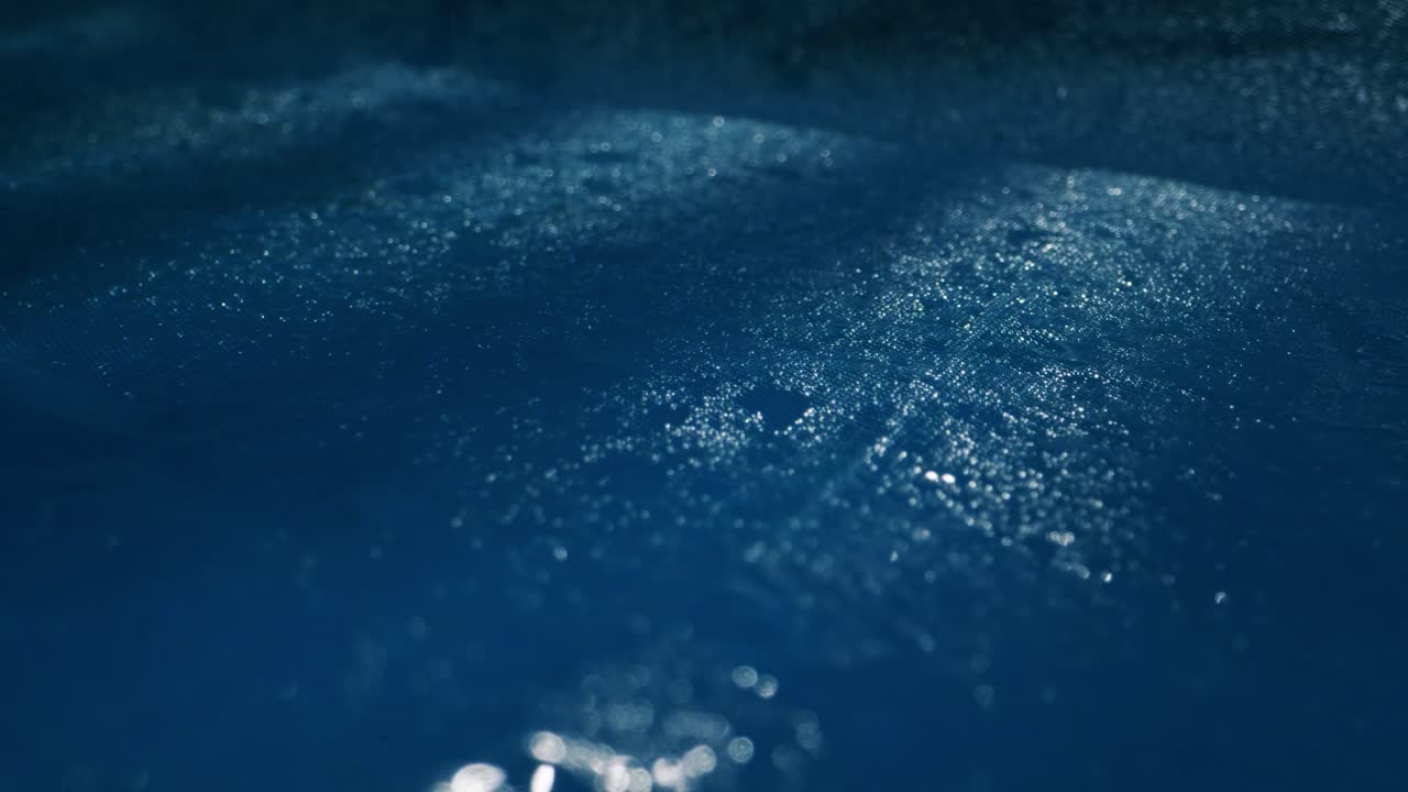 A serene water surface with gentle ripples and glistening raindrops in calming blue hues, creating peace