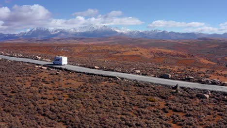 Motorhome-Traveling-On-The-Road-With-Snowy-Mountains-In-The-Distance-Near-Xinduqiao,-Sichuan,-China