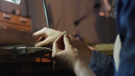cerca de las manos de la joyera caucásica haciendo joyas en el taller