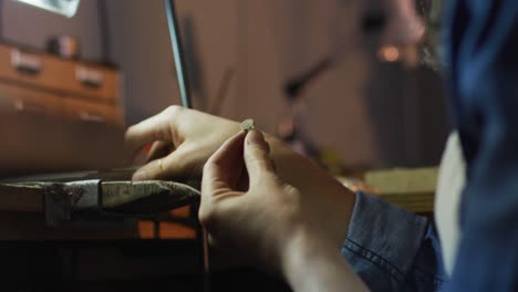 close up of hands of caucasian female jeweller making jewelry in workshop