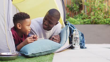 Video-Eines-Glücklichen-Afroamerikanischen-Vaters-Und-Sohnes,-Der-Im-Zelt-Im-Garten-Spielt