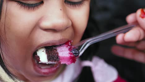 a young girl enjoys a delicious slice of cake with whipped cream and berries