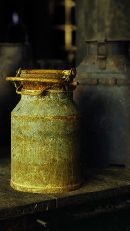 vintage milk cans on rustic wooden table in a dimly lit barn