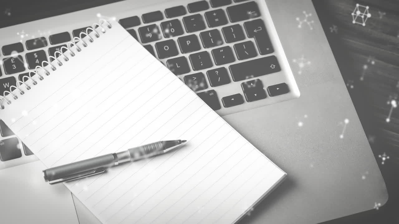 Animation of molecules moving over laptop, notebook and pen on desk