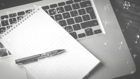 animación de moléculas que se mueven sobre el portátil, el cuaderno y el bolígrafo en el escritorio