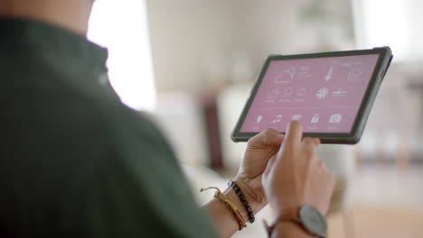 biracial man using tablet with smart home on screen at home, slow motion