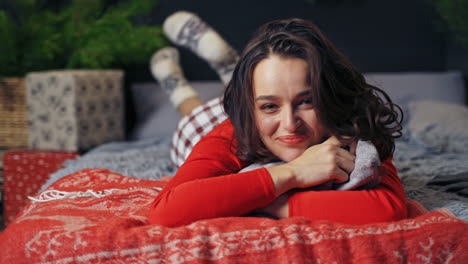happy girl on bed at christmas. young woman on bed resting at home with pillow at new year time. joyful mood of a pretty female at christmas.