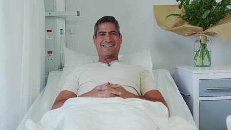 Front-view-of-Caucasian-male-patient-relaxing-on-hospital-bed-in-hospital-ward-4k