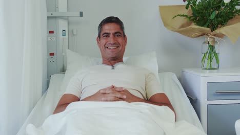 front view of caucasian male patient relaxing on hospital bed in hospital ward 4k