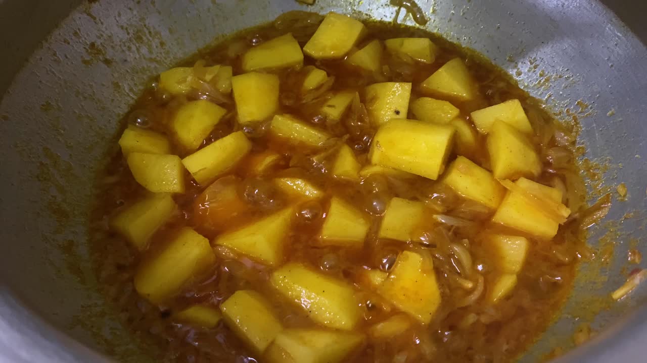 salsa de curry burbujeante con patatas cortadas en dados en una olla grande