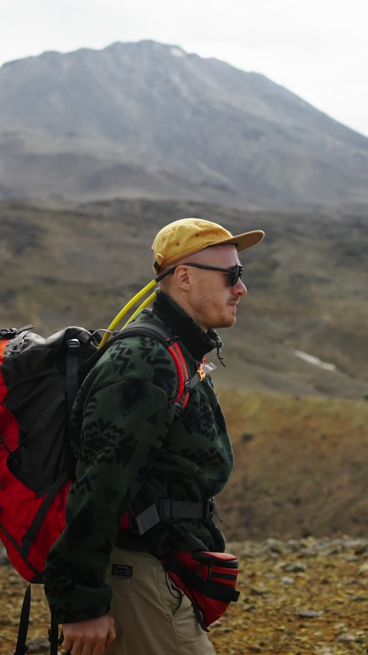 Hombre senderista con mochila y cámara caminando en un paisaje montañoso
