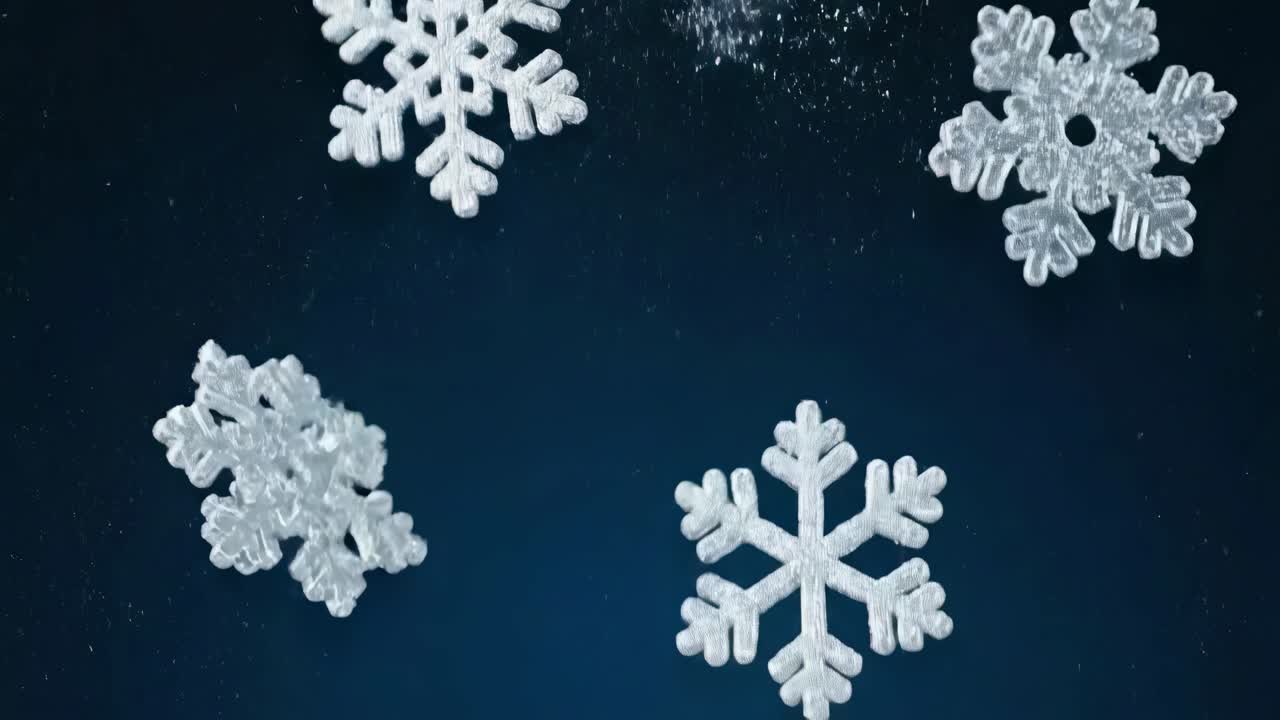 Close-up video of falling snowflakes against a dark background, captured from a low angle
