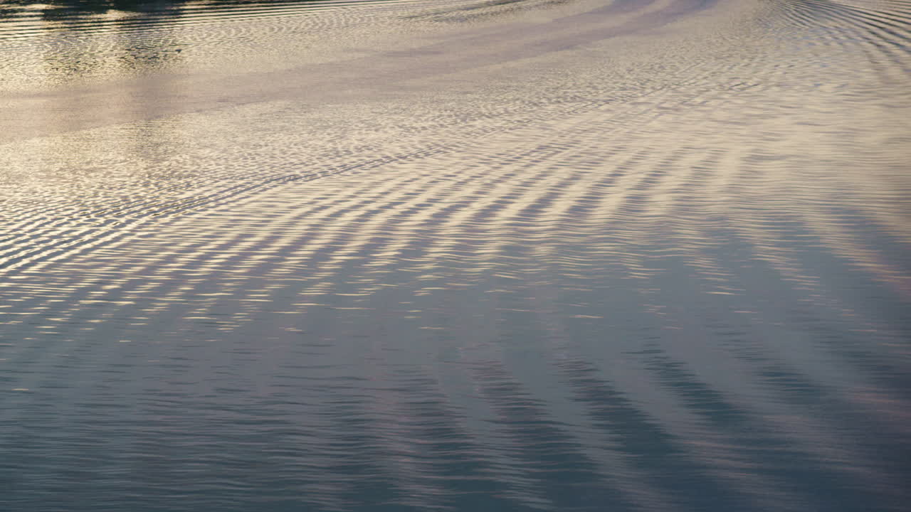 Wavy river ripples flowing drone shot. Sunlight glares moving at calm pace.