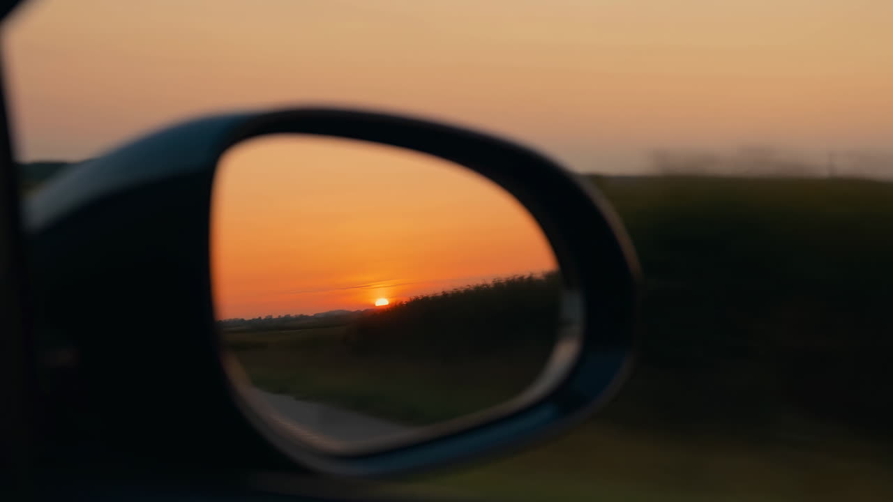 Sunset Reflected In Car Side Mirror, Blurred Countryside Passing During Dusk Drive, Warm Orange Sky Meeting