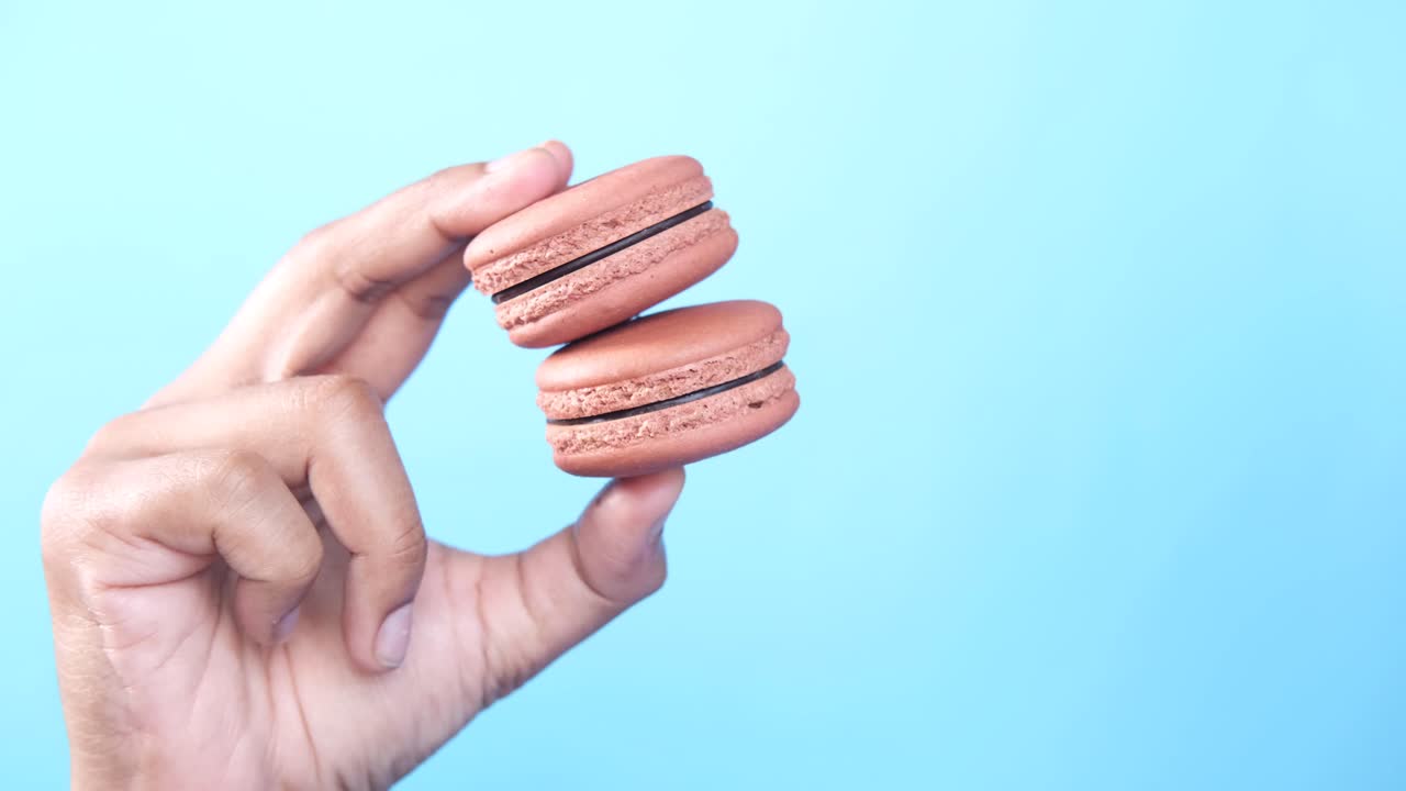 mano con dos macarrones de chocolate