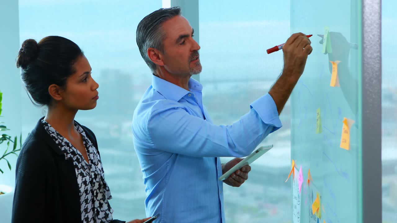 ejecutivos leyendo notas adhesivas en tablero de vidrio