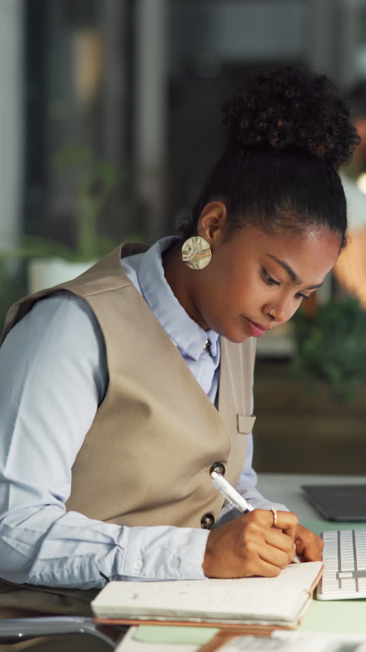 Young Woman Writing Notes in a Notebook at Her Office Desk