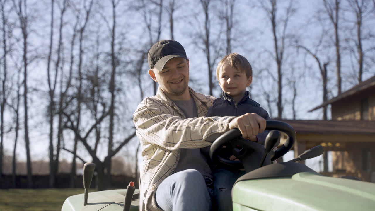 кавказский мужчина едет на квадроцикле с сыном в сельской местности